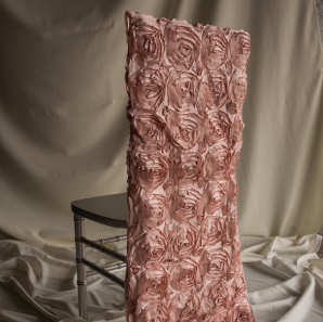 Blush rose colored rosette chair cover on a silver colored Chiavari chair in front of a white back drop.