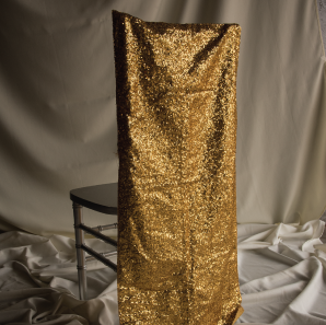 Gold sequined chair cover on a silver colored Chiavari chair in front of a white back drop.