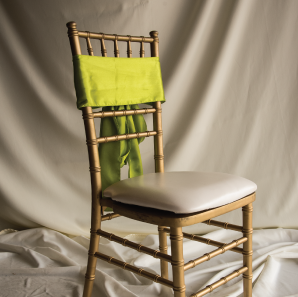 Front of a lime green colored chair sash tied into a bow on a silver chair.