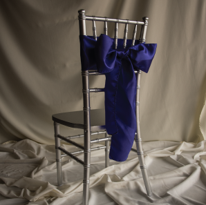 Royal blue chair sash on a silver Chiavari Chair in front of a white backdrop.