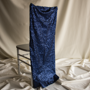 Royal blue sequined chair cover on a silver colored Chiavari chair in front of a white back drop.