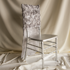 Silver rosette chair cover on a silver colored Chiavari chair in front of a white back drop.